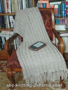 a blanket sitting on top of a wooden chair in front of a bookshelf