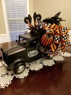 an old truck decorated with halloween decorations on top of a wooden table in front of a window