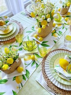 the table is set with lemons and flowers in vases on paper napkins