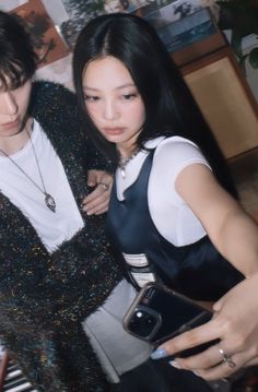 two young women standing next to each other in front of a piano keyboard and looking at their cell phones