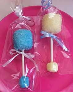 two candy lollipops on a pink plate with blue and white candies