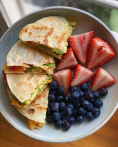 a bowl filled with fruit and quesadillas on top of a wooden table