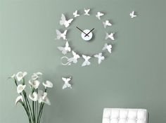 a clock that is on the wall next to a vase with white flowers in it