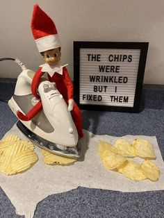 an elf is ironing chips next to a sign that says the chips were wrinkled but i fixed them