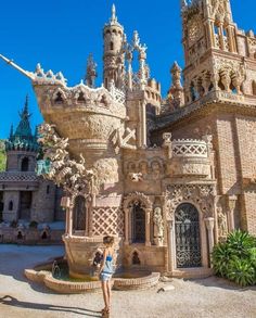 a woman standing in front of a castle like building with statues on the outside and inside