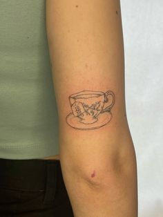 a woman with a tattoo on her arm holding a coffee cup