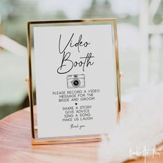 a sign that says video booth on top of a wooden table in front of a window