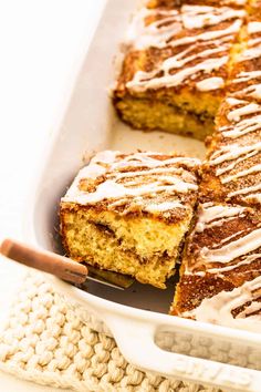 a close up of a cake in a pan with frosting on top and cinnamon sticks