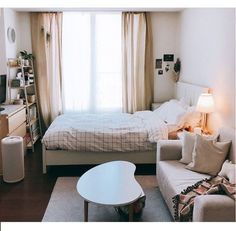 a bed sitting next to a white couch in a living room under a large window