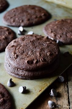 chocolate cookies with white and black speckles are on a baking sheet, ready to be eaten