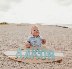 a baby sitting on top of a surfboard with the word mason painted on it