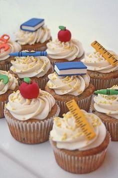 cupcakes with white frosting and school supplies on them are arranged on a plate