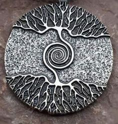 a silver pendant with a tree on it's center and swirls in the middle