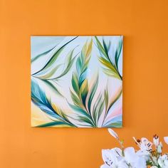 a painting hanging on the wall next to a vase with white flowers in front of it