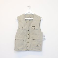 "SKU - DM6231 Vintage Even river vest in Grey. Best fits L DETAILS  ▫️ Button up  ▫️ Pockets   👕 Fits like a ~ L ▫️ Label states ~ L ▫️ Pit to Pit ~ 21\" ▫️ Length ~ 25\" ▫️ Pit to Cuff ~ N/A   👇 If any defect is found and it is not included in the provided photos, it will be listed below. ▫️      🧺 All items are professionally washed and ironed before photos are taken and then sold.    ✅ If the item is listed, it is available   ❌ Disclaimer: Like all vintage items they may have slight imperfections and defects that can go unseen while listing. However, each item is washed before listing and all discovered defects will be noted above." Casual Button-up Vest Outerwear, Cotton Button-up Vest, Spring Sleeveless Vest With Snap Buttons, Cotton Button-up Vest With Buttons, Casual Denim Vest With Button Closure, Casual Cotton Vest With Snap Buttons, Utility Sleeveless Tops With Pockets, Casual Button-up Vest For Work, Sleeveless Utility Top With Pockets