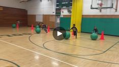 an indoor basketball court with green and yellow cones on the floor, while people are playing ball