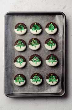 cookies decorated with green and white frosting in the shape of trees on a baking sheet