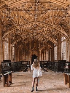 a woman is standing in the middle of a large room with wooden ceilings and tables