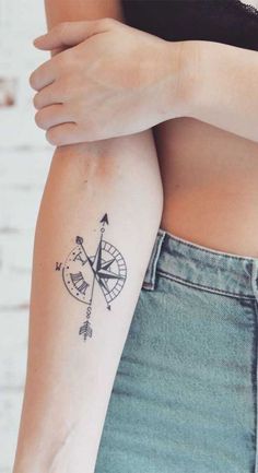 a woman's arm with a tattoo on it that has an arrow and compass