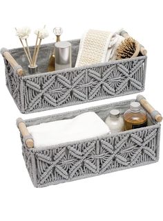 two gray baskets with towels, soaps and other items in them on a white background