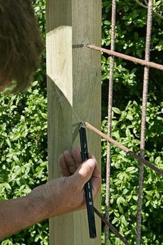 a man is measuring the length of a wooden fence post with a tape measure ruler