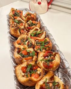 many small pizzas are lined up on a tray