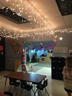 an empty classroom with lights strung from the ceiling and decorations on the wall above it