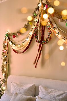 a christmas tree hanging from the side of a wall next to a bed with white pillows