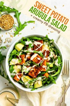 a white bowl filled with salad next to a fork and spoon on top of a table