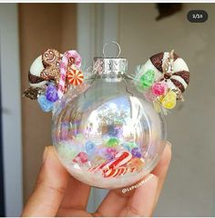 a hand holding a glass ornament with candy on it