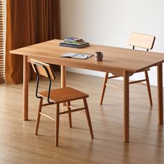 a wooden table with two chairs next to it and a book on top of the table