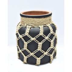 a black and white vase with rope wrapped around the bottom, on a white background