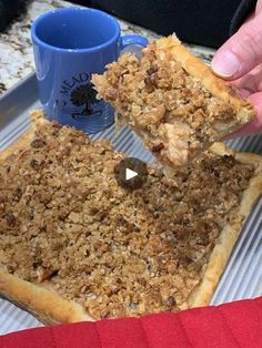 a person holding a piece of food over a tray with a coffee cup on it