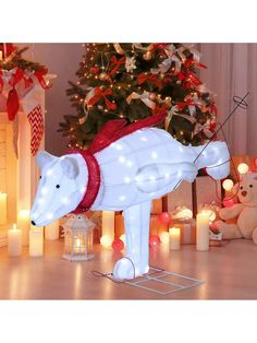 a lighted polar bear standing in front of a christmas tree with candles and decorations around it