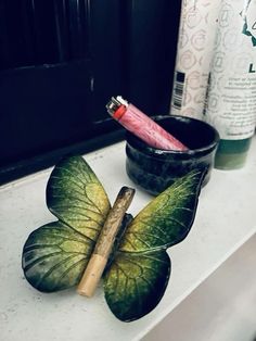 a toothbrush in a cup next to a leaf shaped candle holder on a counter