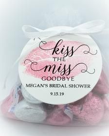 a small bag filled with pink and white candies next to a tag that says kiss the miss goodbye