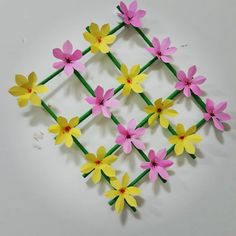 the paper flowers are arranged on sticks and placed in a square pattern with green stems