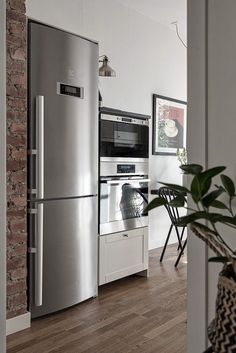 a silver refrigerator freezer sitting inside of a kitchen next to a potted plant