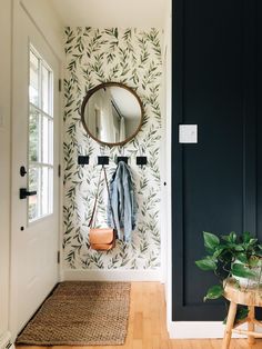 a mirror hanging on the wall next to a wooden bench and plant in front of it