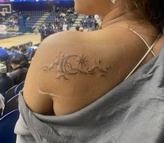 a woman with a tattoo on her shoulder in front of a basketball court and audience