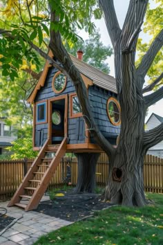 a tree house built into the side of a tree in front of a wooden fence