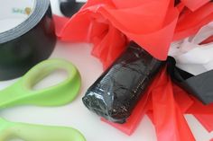 scissors, tape and other crafting supplies on a white counter top with red tissue