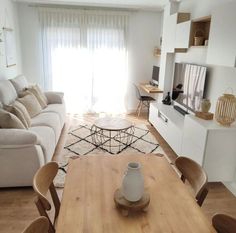 a living room filled with furniture and a wooden table in front of a tv mounted on a wall