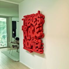 there is a red sculpture on the wall in this living room that says, here's no place at home