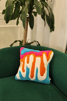 a green chair with a pillow on it and a plant in the corner behind it