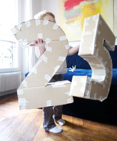 a child holding up a cardboard number 2