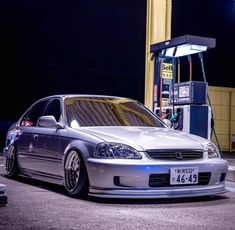 a silver car parked in front of a gas pump