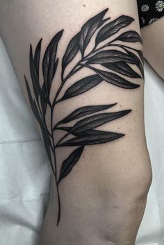 a black and white photo of a woman's leg with leaves on it