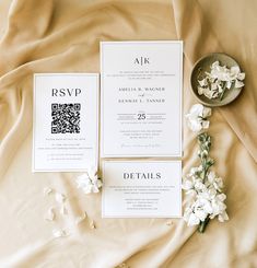 the wedding stationery is laid out on top of the bed with white flowers and greenery