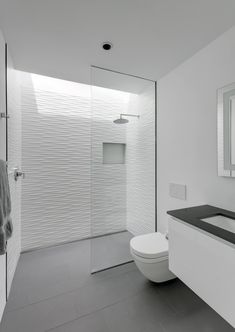 a bathroom with a toilet, sink and shower stall is shown in black and white